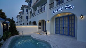 A hotel named Memory Villa with a pool area, a balcony, and a well-lit entrance.