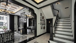 A spacious living area with a black and white color scheme, a staircase, and a view of the outside.