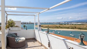 Un balcón con vista al mar, una silla y una lámpara.