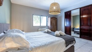 Un dormitorio con cama, armario, ventana y lámpara colgante.