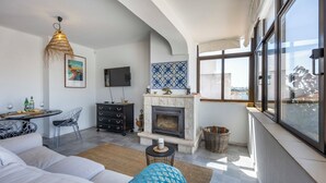 Una sala de estar moderna con chimenea, un televisor montado en la pared y un ventanal con vistas a la ciudad.