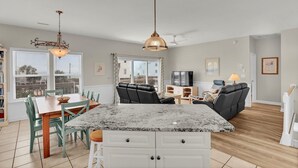 A spacious living area with a kitchen island, dining table, and seating.