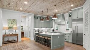 A spacious kitchen with a large island, pendant lighting, and a rustic ceiling. - Welcome to Azalea Abbey! Private Pool, Golf Cart, Walk to Beach, Seaside (Santa Rosa Beach)