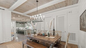 A dining area with a wooden table, benches, and a chandelier. - Welcome to Azalea Abbey! Private Pool, Golf Cart, Walk to Beach, Seaside (Santa Rosa Beach)