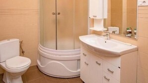 Un baño con inodoro, cabina de ducha y tocador con espejo.