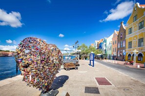 Un muelle con edificios de colores, una gran escultura hecha de llaves, y un pequeño bote amarrado cerca.