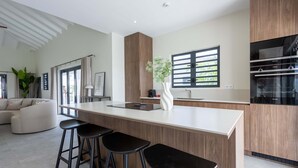 Una cocina moderna con una isla central, taburetes de bar y un ventanal grande.