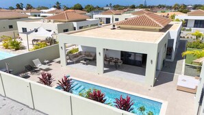 Un complejo residencial moderno con piscina, mobiliario exterior y vistas a viviendas vecinas.