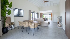 Un amplio espacio de estar con una mesa de comedor, sillas y una planta grande en maceta.