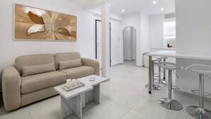 A modern living room with a beige sofa, a coffee table, and a bar area with stools. - Acropolis Museum Apartment by A&A Residences (Athens)