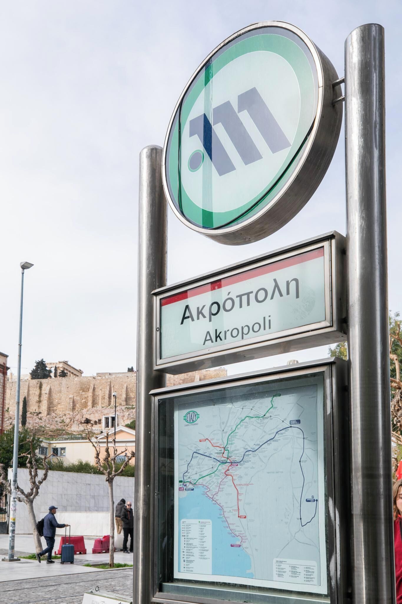 A bus stop sign with a map and the name "Akropoli".