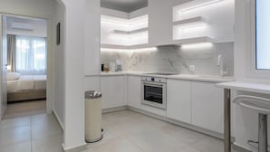 A modern kitchen with white cabinetry, a marble countertop, and built-in lighting. - Acropolis Museum Apartment by A&A Residences (Athens)