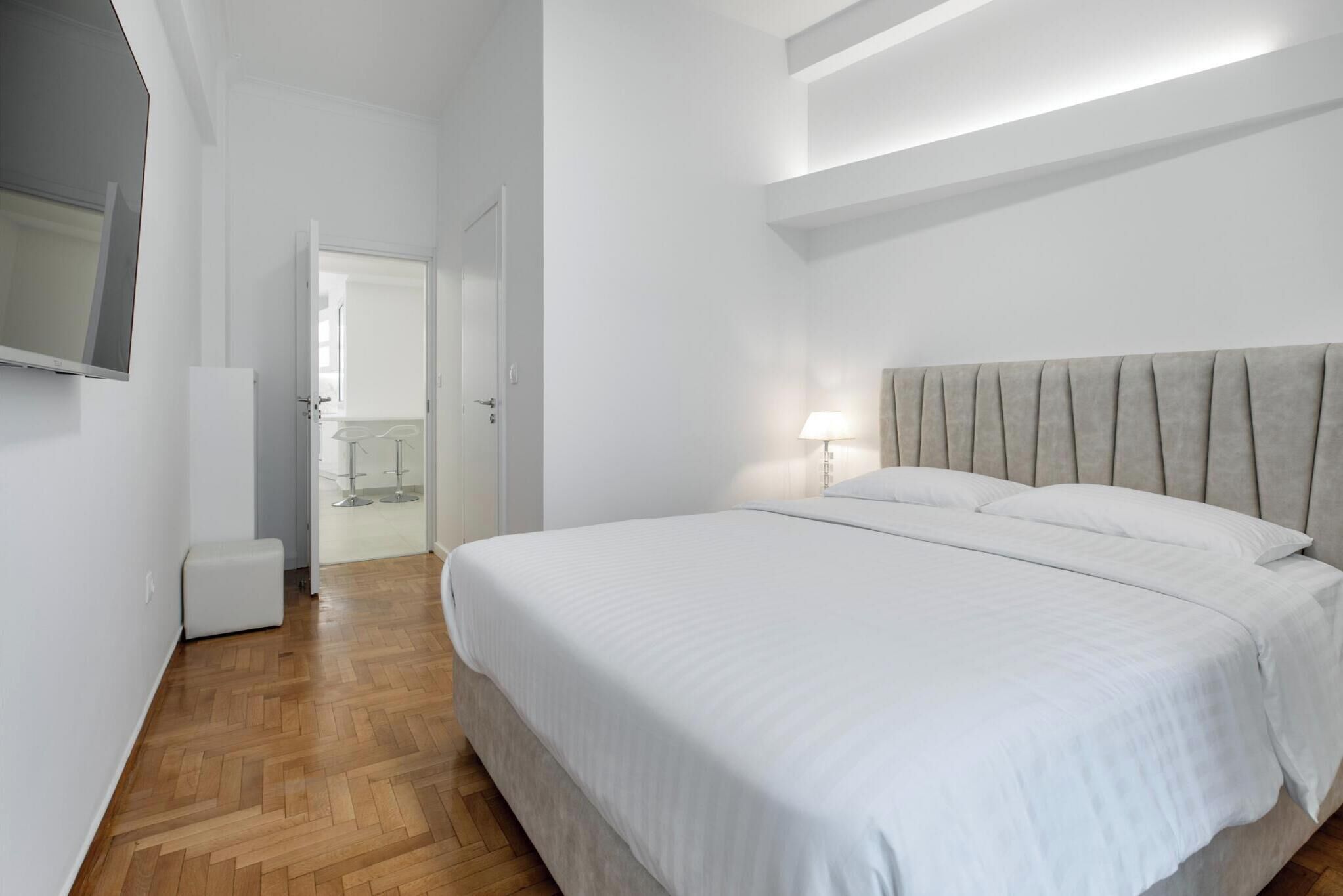 Una camera da letto con un letto grande, un comodino e una TV montata a parete.