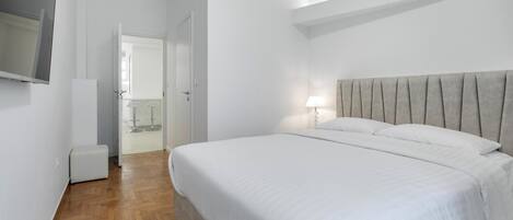 Una camera da letto con un letto grande, un comodino e una TV montata a parete.