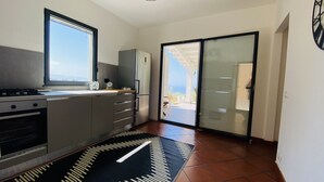 A modern kitchen with a gas stove, a refrigerator, and a large window. - Tenute Lomasi - near Cefalù with swimming pool (Lascari)
