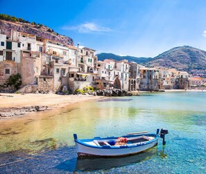 A coastal village with traditional stone buildings, a clear blue sea, and a small boat docked at the shore. - Tenute Lomasi - near Cefalù with swimming pool (Lascari)