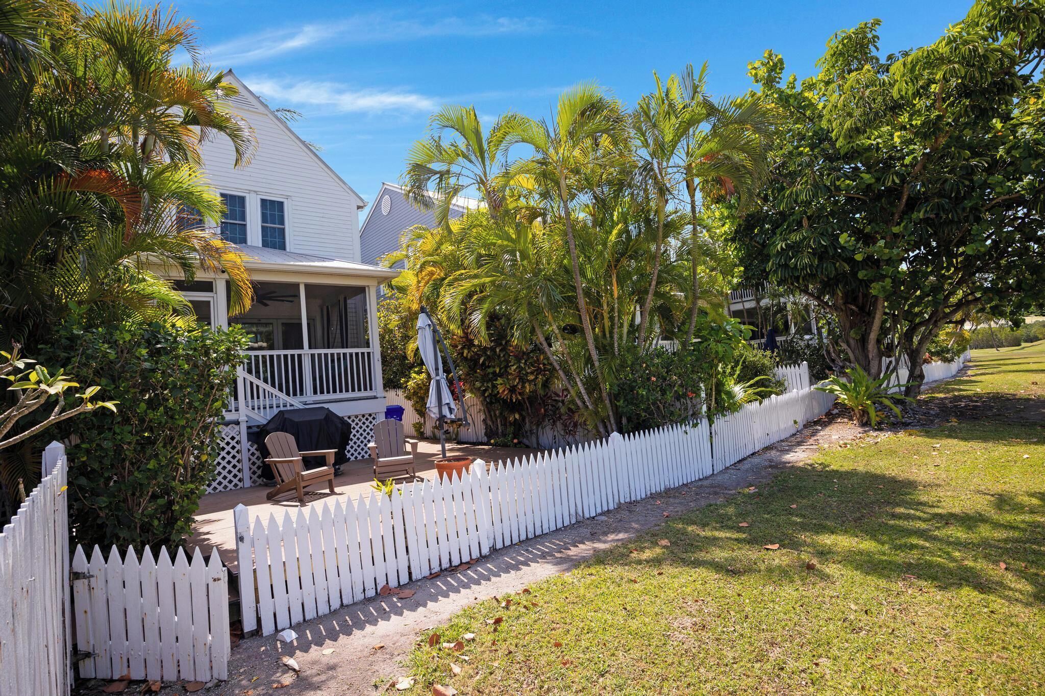 A house with a covered porch, a white picket fence, and a lawn.
