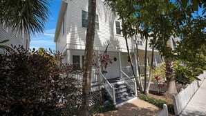 A two-story house with a front porch, a staircase, and a white picket fence.