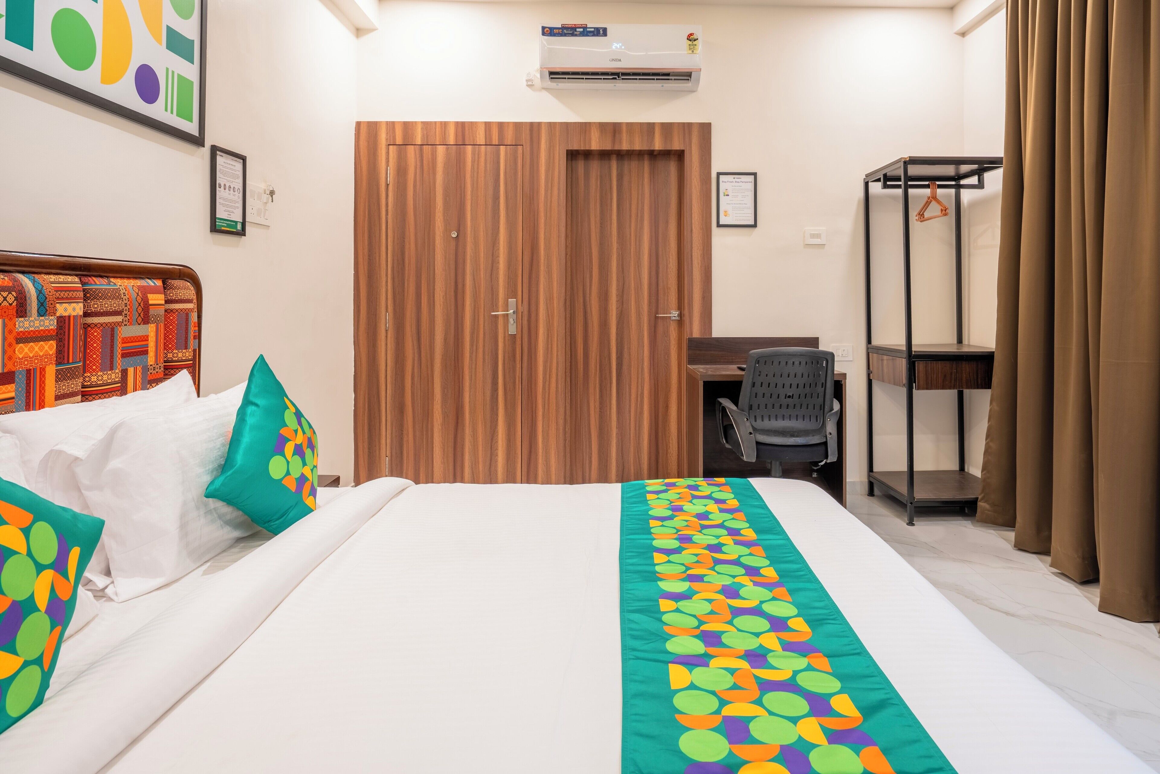 Habitación de hotel con cama, escritorio, armario y una silla colgante.