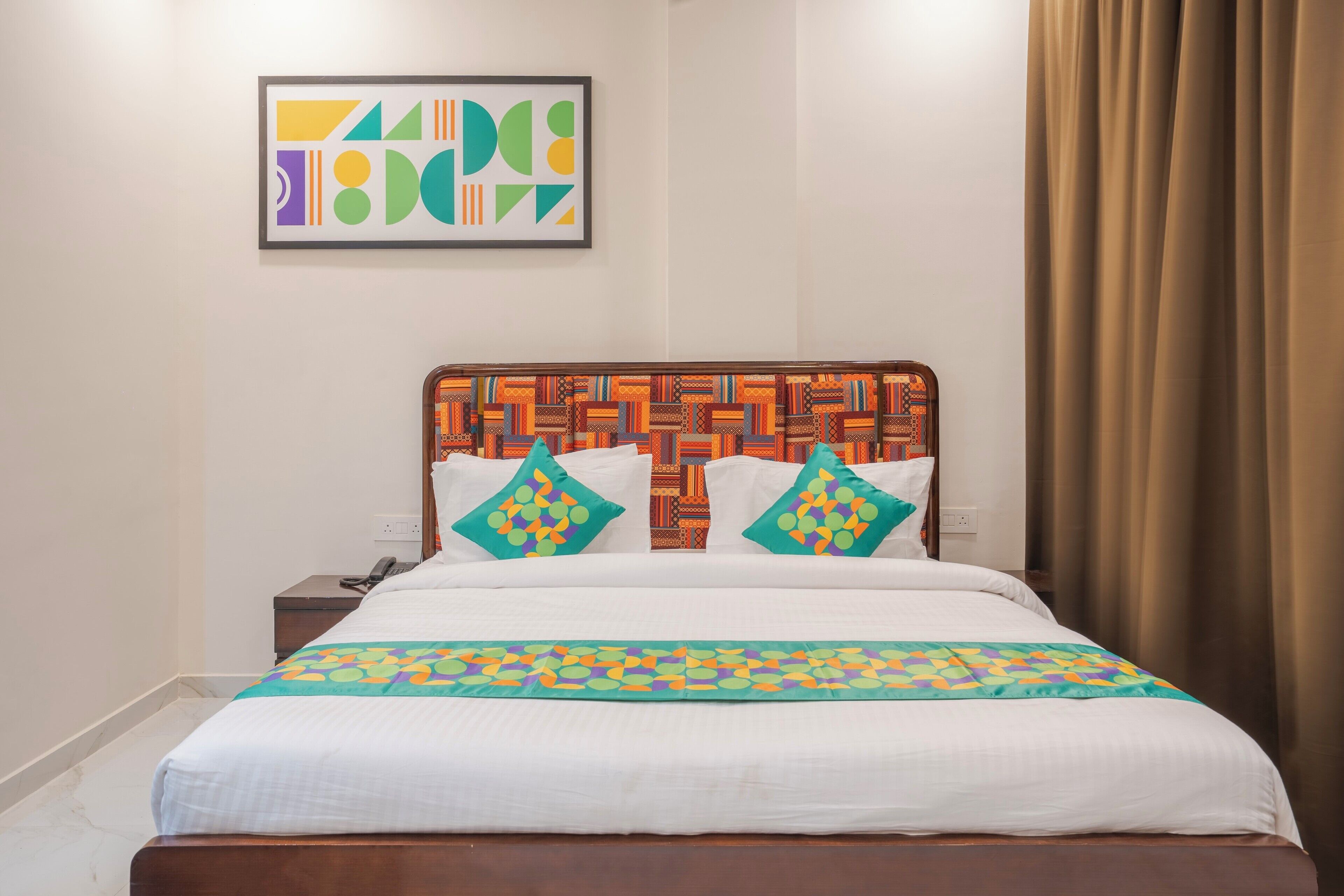 A neatly made bed with a patterned bedspread, a decorative headboard, and two pillows with geometric designs.