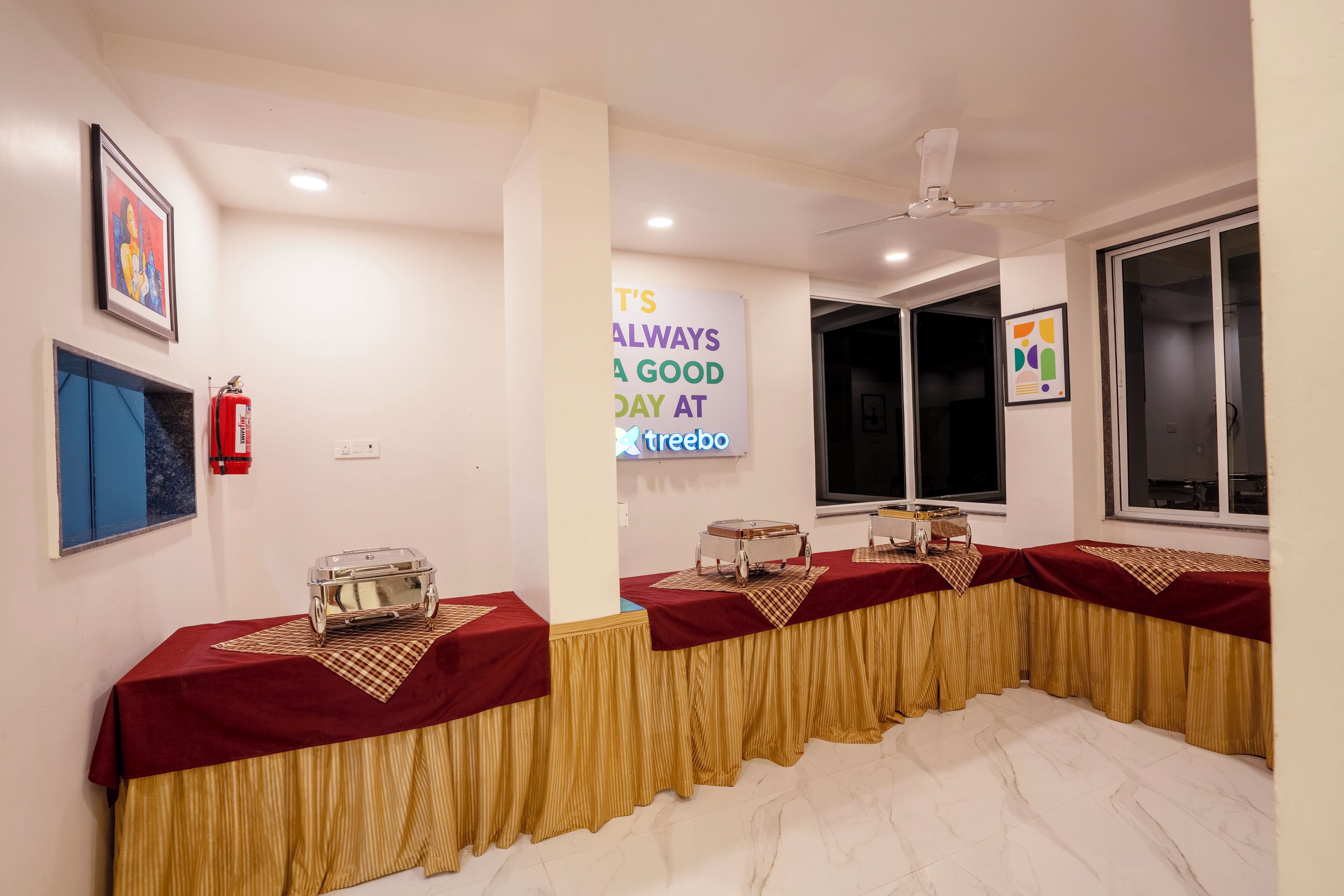 A conference room with tables covered in red and gold tablecloths, equipped with vintage radios.