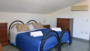 Une chambre à coucher comprenant un lit, deux tables de chevet, une commode, un climatiseur et une lampe.
