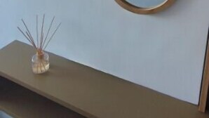 Eine Wand mit zwei Spiegeln und einem kleinen Regal mit einem dekorativen Gegenstand.