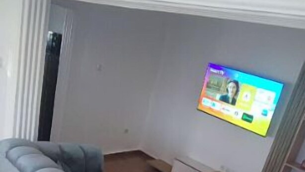 Ein modernes Wohnzimmer mit einem großen grauen Sofa, einem kleinen runden Tisch und einem an der Wand befestigten Fernseher.