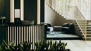 A reception area with a modern desk, a staircase, and a view of the outdoors.