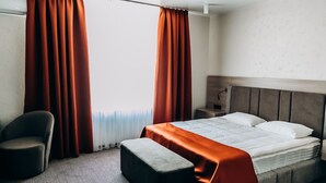 A hotel room with a bed, a chair, and a bench.