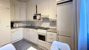 A compact kitchen with white cabinets, a Bosch microwave, a sink, and a refrigerator.