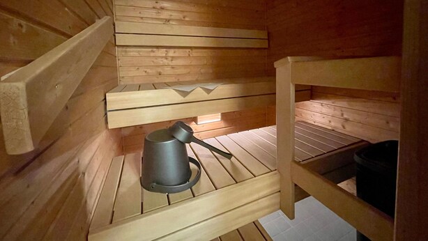 A wooden cabin with a bunk bed, a small table, and a kettle.