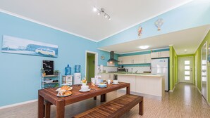 A modern kitchen with a dining area, featuring a wooden table, bench, and a kitchen island. - Break-A-Way COASTAL COMFORT IN LANCELIN (Lancelin)