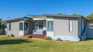 A single-story mobile home with a front porch, a sliding door, and a small patio area with a couch. - Break-A-Way COASTAL COMFORT IN LANCELIN (Lancelin)
