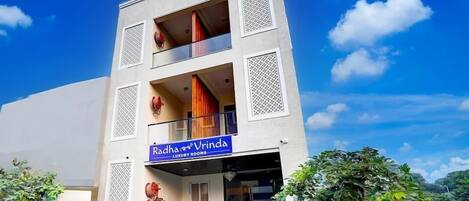 A multi-story building with a sign reading "Radha & Vrinda Luxury Rooms".