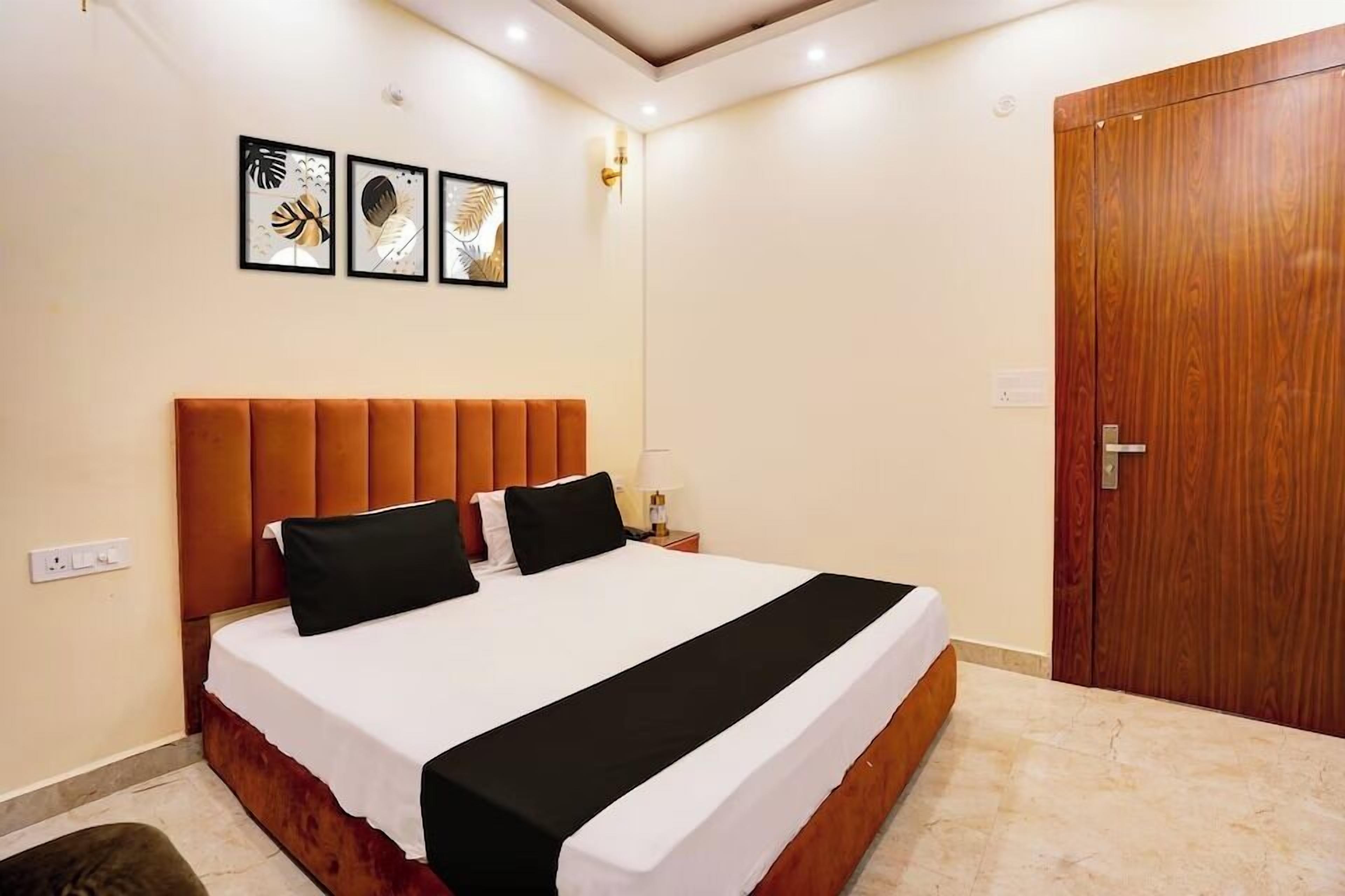 A bedroom with a large bed, a wooden wardrobe, and three framed pictures on the wall.