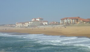 Un hotel frente a la playa con varias edificaciones, una playa de arena y el océano.
