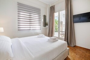 Une chambre d’hôtel avec un lit, un téléviseur fixé au mur, une fenêtre avec des stores et une vue sur l’extérieur.