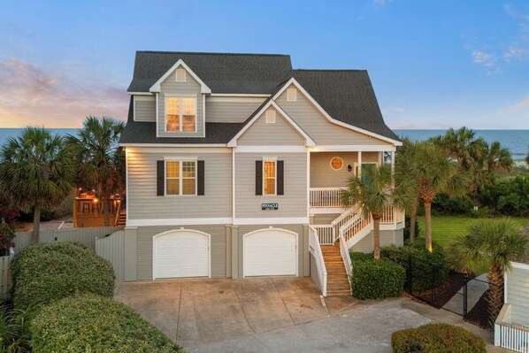 A two-story house with a front porch, a garage, and a view of the ocean.