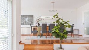 Un salon moderne avec un escalier en bois, un coin repas avec une table et des chaises, et une plante en pot.