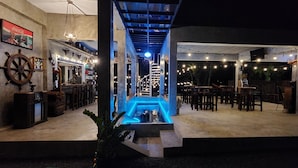 A bar area with a staircase leading to a pool, surrounded by tables and chairs. - Seven 50s (Pai)