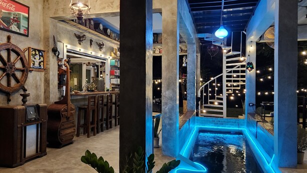 A bar area with a vintage decor, including a ship's wheel and a Coca-Cola sign. - Seven 50s (Pai)
