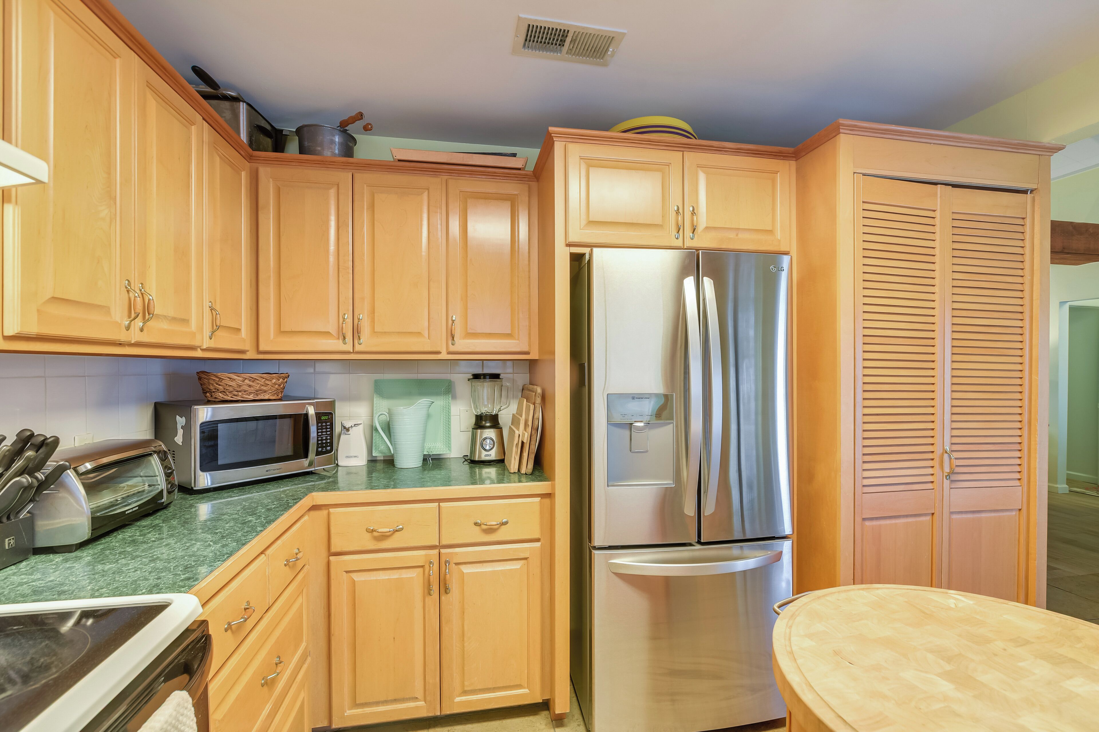 A kitchen with wooden cabinets, a stainless steel refrigerator, a microwave, and a sink.