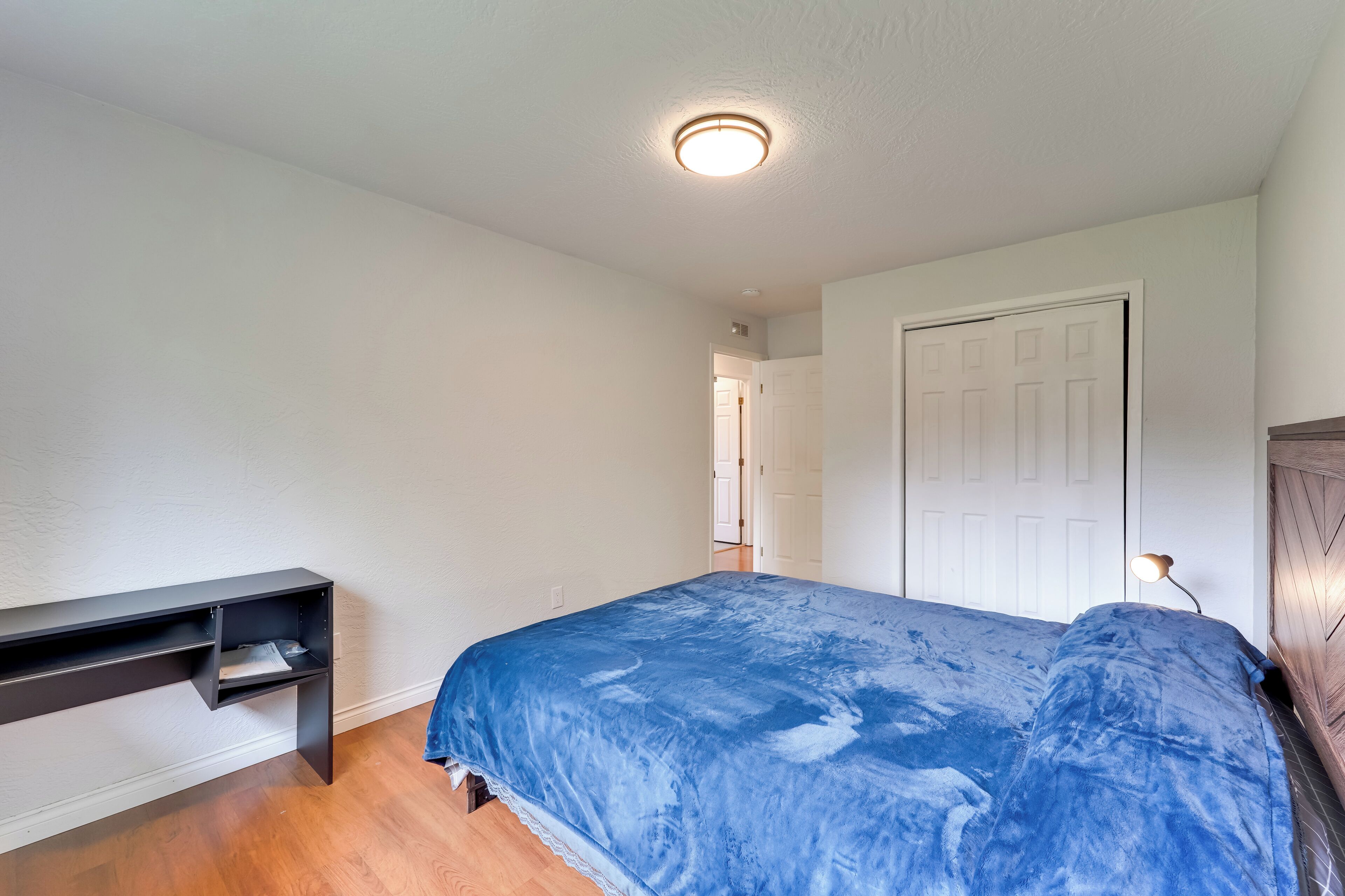 Un dormitorio con cama, escritorio y puerta.