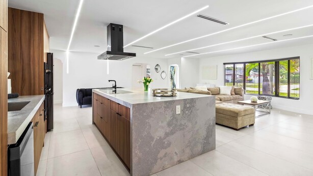 A modern kitchen with a central island, wooden cabinets, and a built-in dishwasher. - Home 6 Mi to Hollywood Beach: Grill, Swim, Relax (Hollywood)