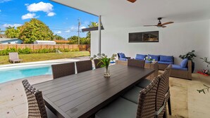 An outdoor patio with a pool, a dining table, wicker furniture, and ceiling fans. - Home 6 Mi to Hollywood Beach: Grill, Swim, Relax (Hollywood)