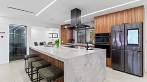 A modern kitchen with a central island, stainless steel appliances, and wooden accents. - Home 6 Mi to Hollywood Beach: Grill, Swim, Relax (Hollywood)