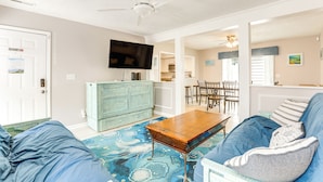 A living room with a blue sofa, a wooden coffee table, a television, and a ceiling fan. - Walk to Ocean & Golf: North Myrtle Beach Home! (North Myrtle Beach)