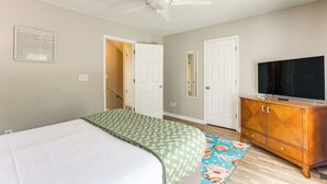 A bedroom with a bed, a ceiling fan, a television on a wooden cabinet, and a door leading to another room. - Walk to Ocean & Golf: North Myrtle Beach Home! (North Myrtle Beach)