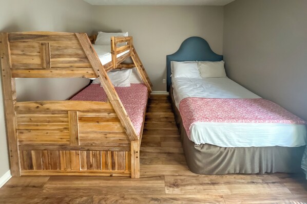 Una habitación con dos camas, una de madera y otra con cabecera azul, y piso de madera.